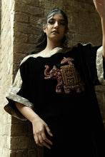 Load image into Gallery viewer, Woman wearing a black outfit with intricate embroidery, standing against a brick wall.
